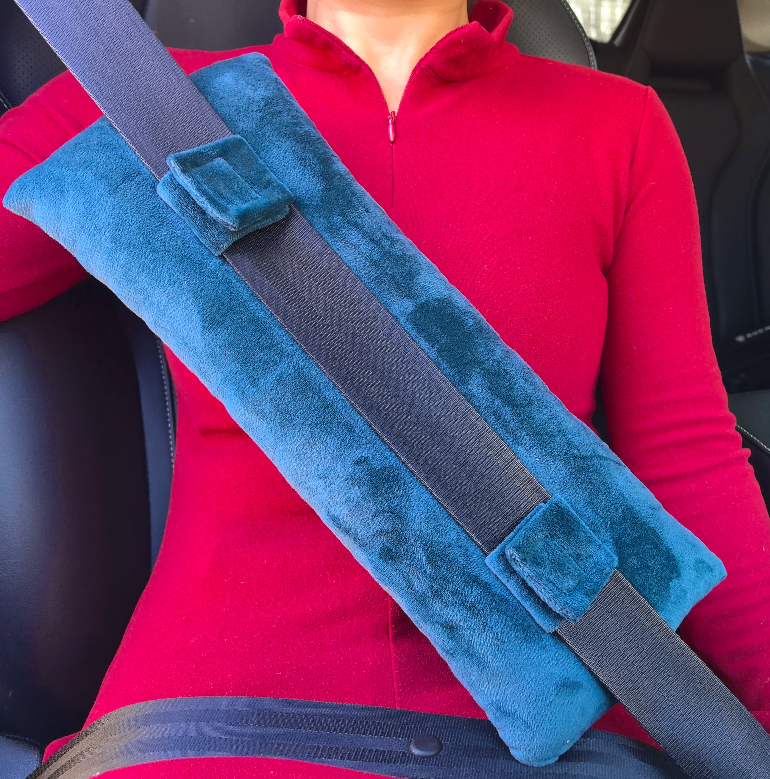 Le protecteur CushionGuard™ installé sur une ceinture de sécurité de voiture, démontrant comment il crée une barrière confortable entre la sangle et le corps.