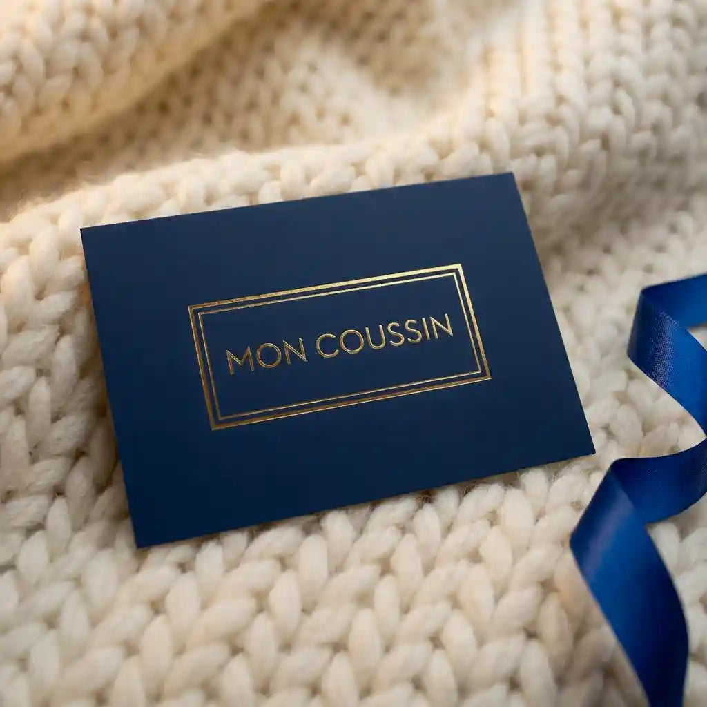 Carte cadeau Mon Coussin élégante bleu marine et or posée sur un plaid en laine douce, le cadeau confort idéal.