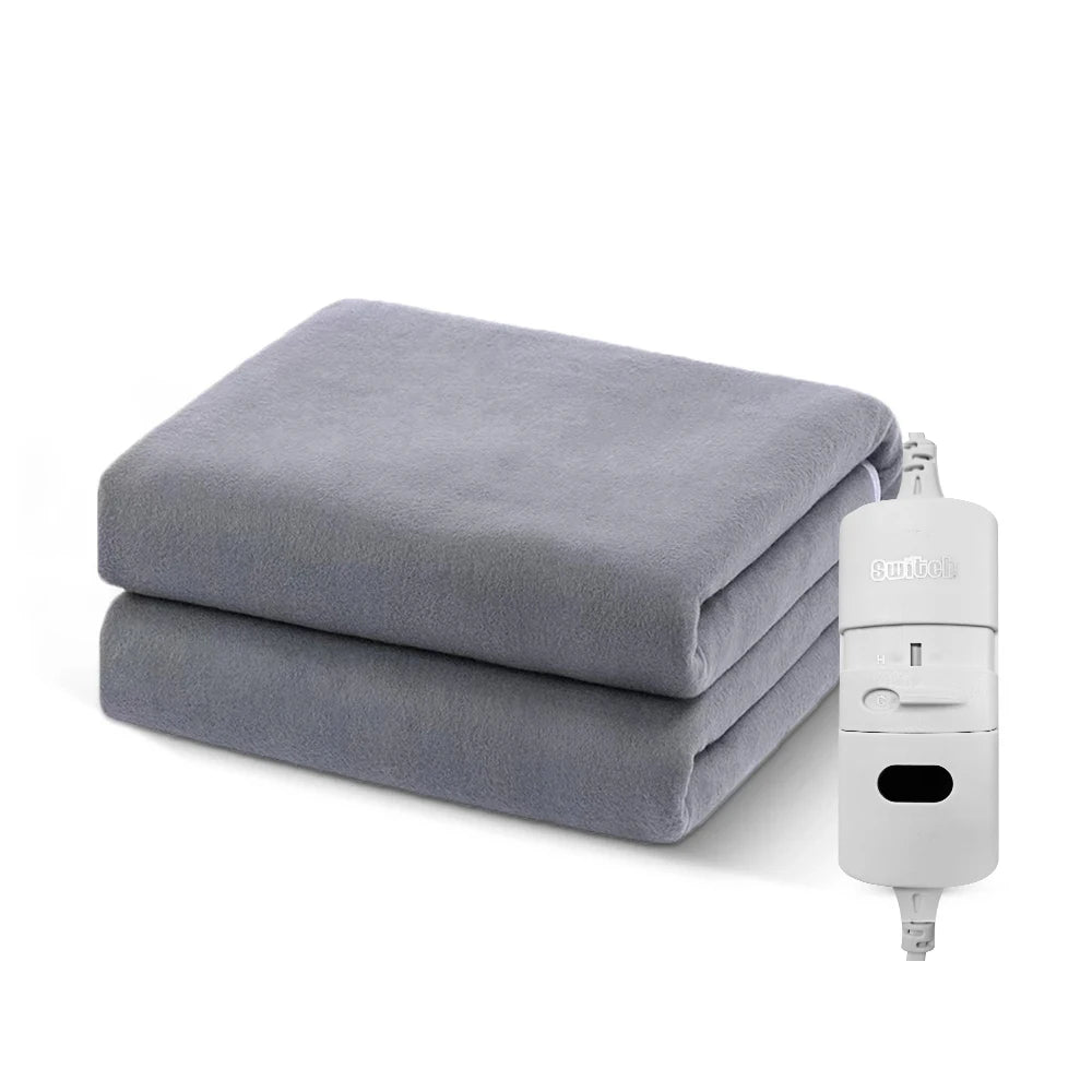 Surmatelas chauffant gris ThermoNuit™ soigneusement plié à côté de sa commande manuelle blanche.